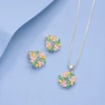 Sterling silver floral pendant and earrings set with multicolour zircon stones displayed on a pastel blue background.