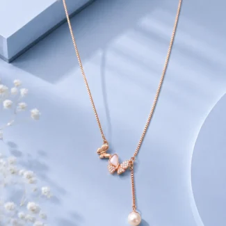 Rose gold butterfly pendant necklace with zircon stones and pearl drop displayed on a soft pastel blue luxury jewellery background.