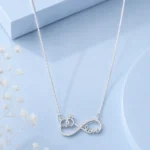 Silver infinity love pendant necklace with zircon detailing displayed on a soft pastel blue luxury background.