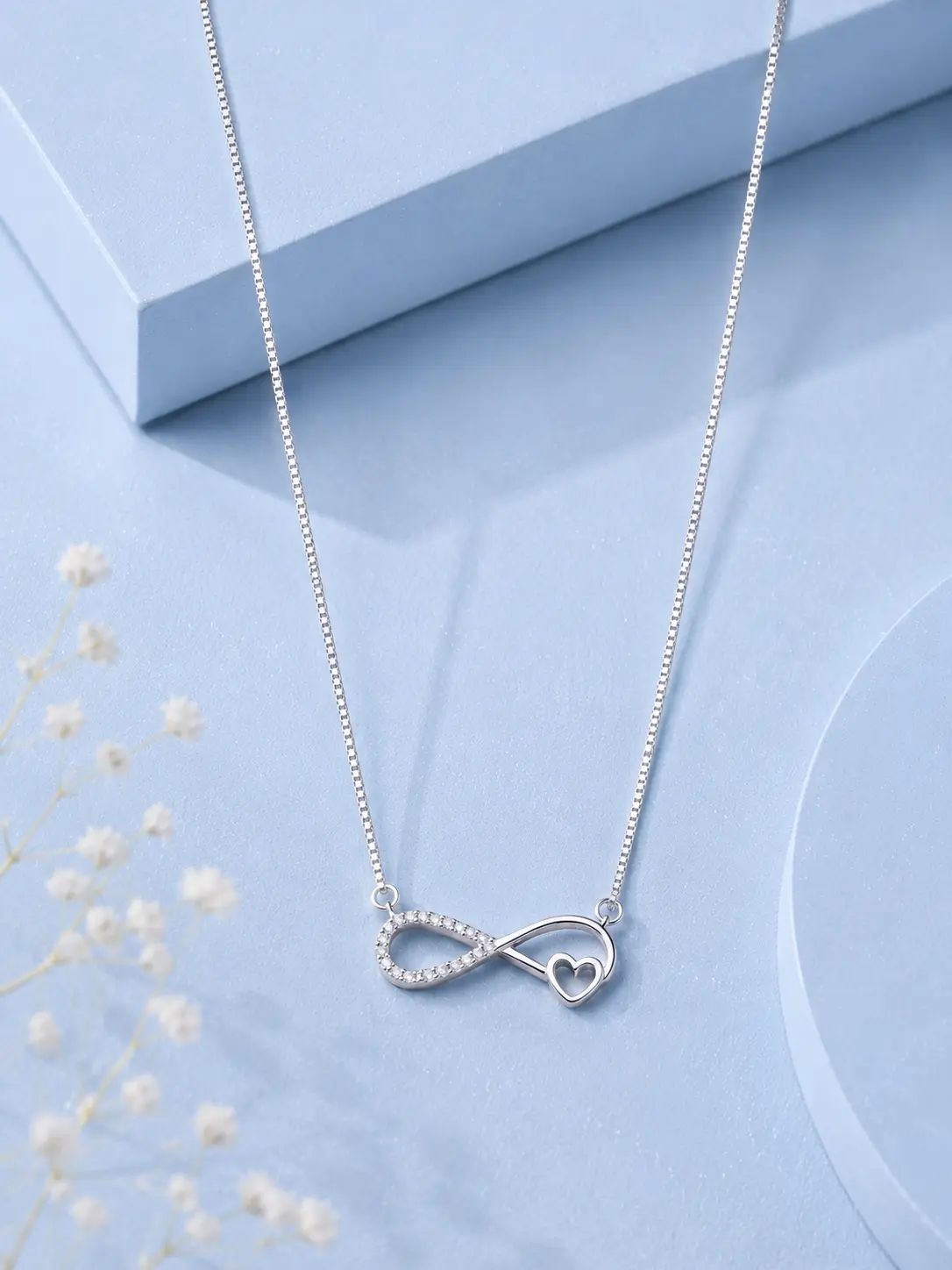 single love silver Silver infinity heart pendant necklace with zircon detailing displayed on a soft pastel blue luxury background.