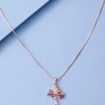 Rose gold bird pendant necklace with pink crystal accents displayed on a soft pastel blue background