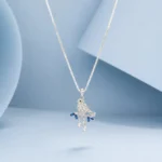 Sterling silver bird pendant necklace with blue crystal accents displayed on a soft pastel blue background.