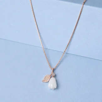 Rose gold floral pendant necklace with ivory flower charm and zircon detailing displayed on a soft pastel blue background.