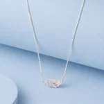 Silver feather pendant necklace with zircon detailing and pearl accent displayed on a soft pastel blue luxury background.