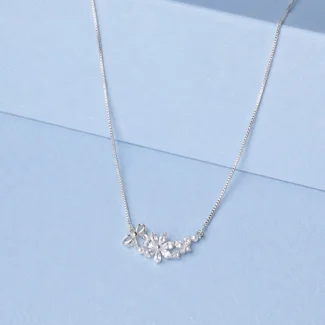 Sterling silver floral necklace with zircon stones and pearl accents displayed on a pastel blue background.
