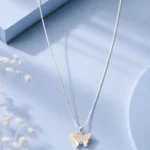 Silver butterfly pendant necklace with iridescent crystal wings displayed on a soft pastel blue luxury jewellery background.