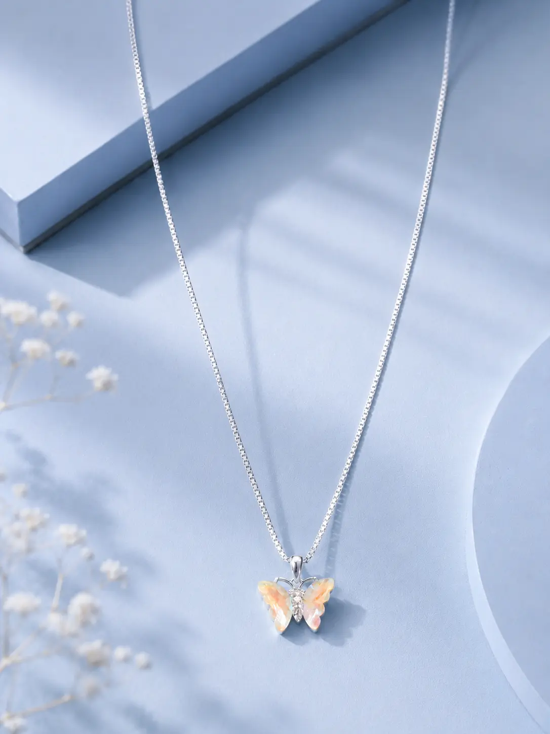 website image single butterfly silver Silver butterfly pendant necklace with iridescent crystal wings displayed on a soft pastel blue luxury jewellery background.